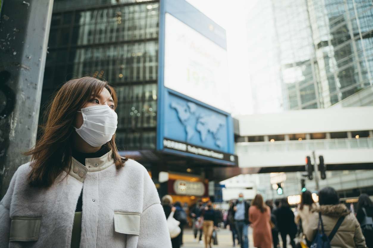 Young Asian woman wearing a protective face mask to prevent the spread of germs and viruses in the city
