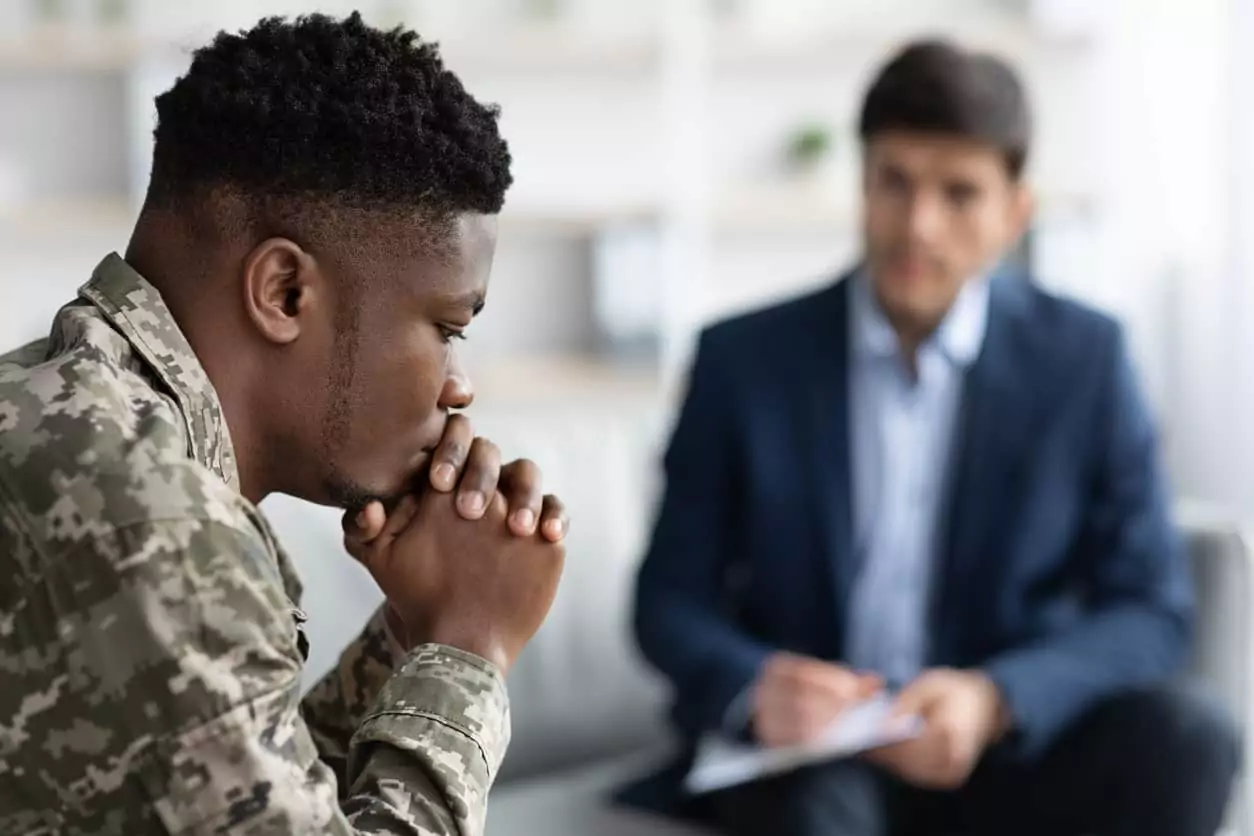 Pensive black soldier having conversation with social worker Young veteran discussing the signs and symptoms of PTSD with his psychiatrist.