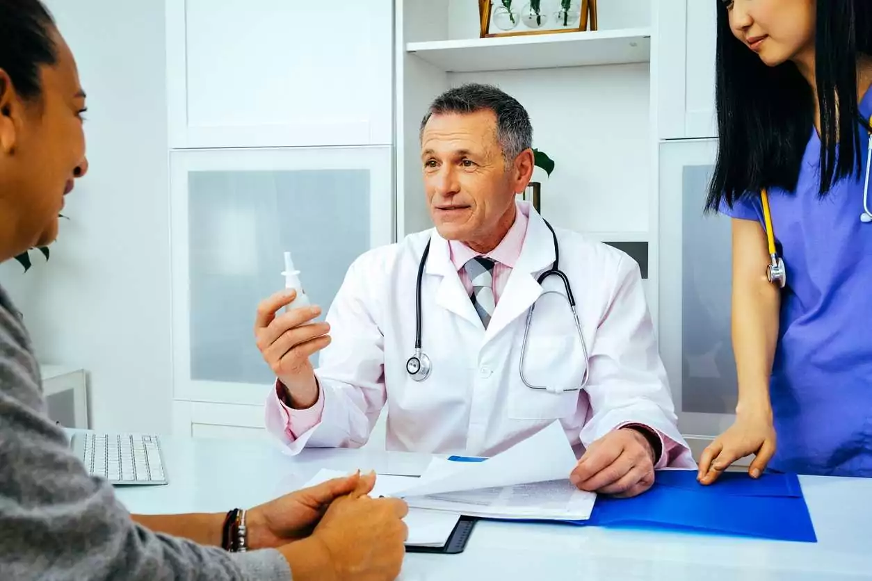 doctor physician and nurse practitioner giving nasal spray to female patient in hospital consultation Doctor and nurse discussing the differences between ketamine and esketamine with their patient