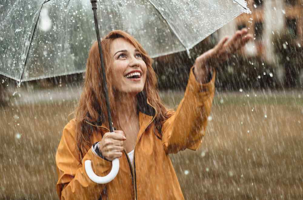 Woman Smiling Under Umbrella in Rain - Metaphor for Depression Relapse Prevention