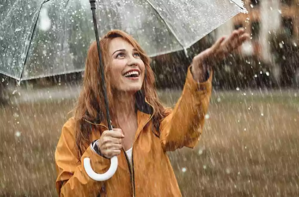 TMS Maintenance Therapy Woman Smiling Under Umbrella in Rain - Metaphor for Depression Relapse Prevention