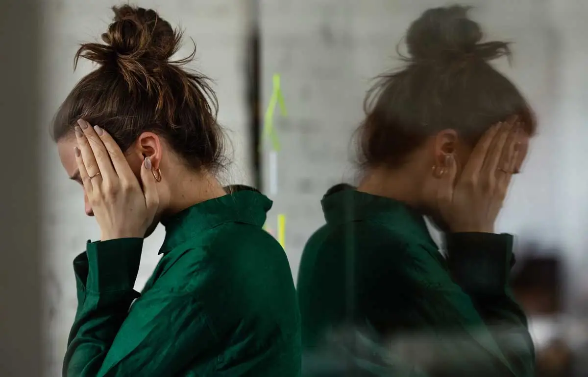 biopolar-disorder-conditions woman back turned to her reflection holding her head