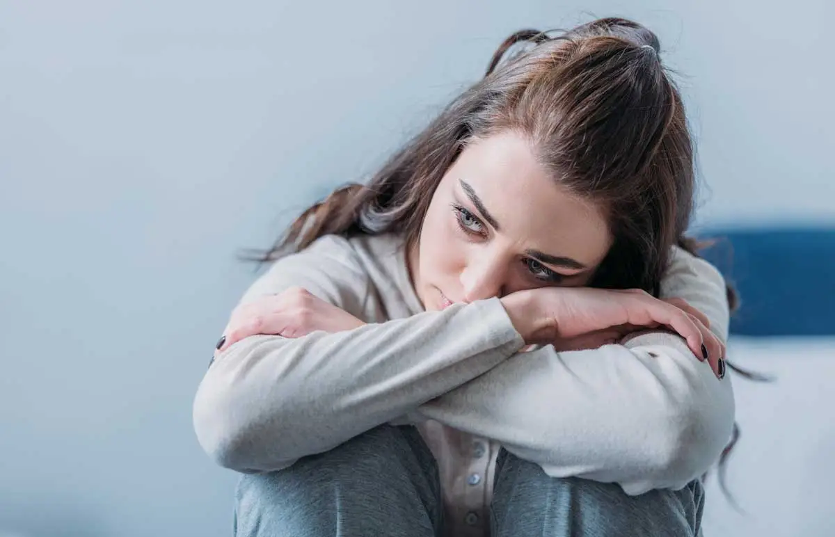 woman sits on couch attempting to cope with racing thoughts