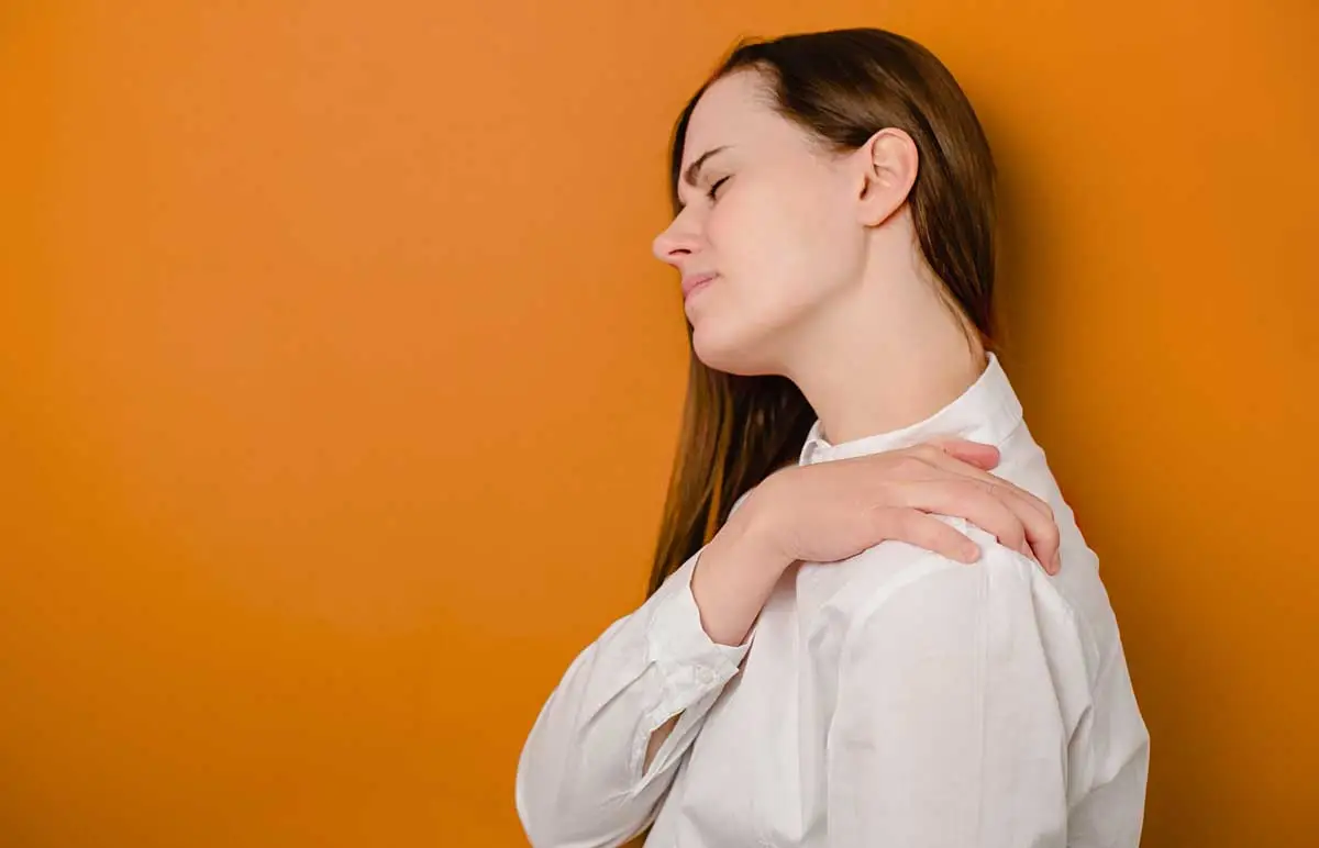 Woman grabbing shoulder in discomfort illustrating fibromyalgia